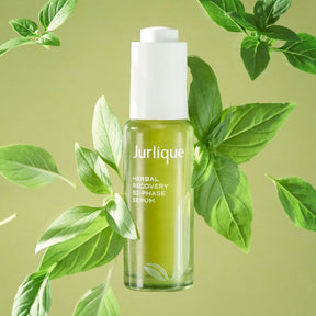 Jurlique Herbal Recovery Two-Phase Serum bottle surrounded by green leaves on a light green background