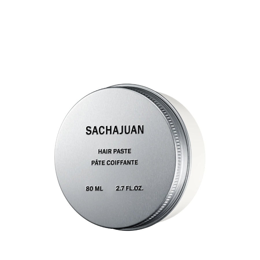A round silver metal tin of SACHAJUAN Hair Paste, showing the top lid with black text and a white container body, on a solid white background.